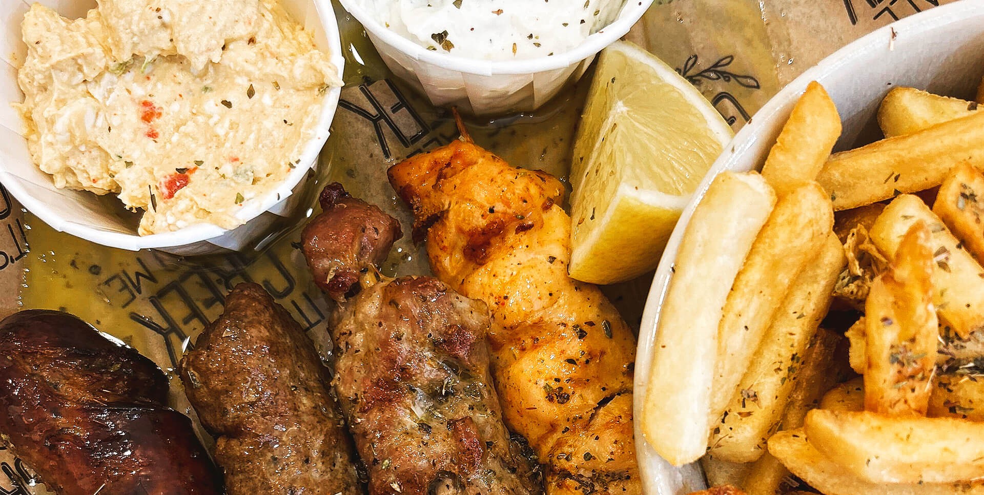 A plate of Greek cuisine featuring fries, grilled meat, and assorted traditional dishes.