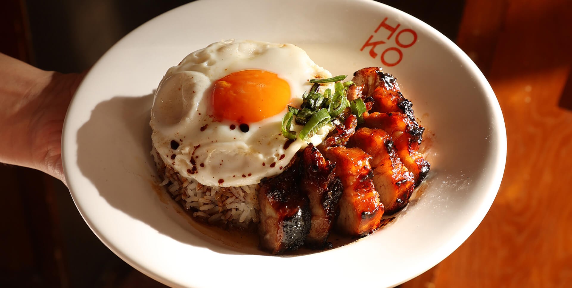 A person holding a plate filled with various hong kong cuisine, showcasing a colourful and appetising meal.