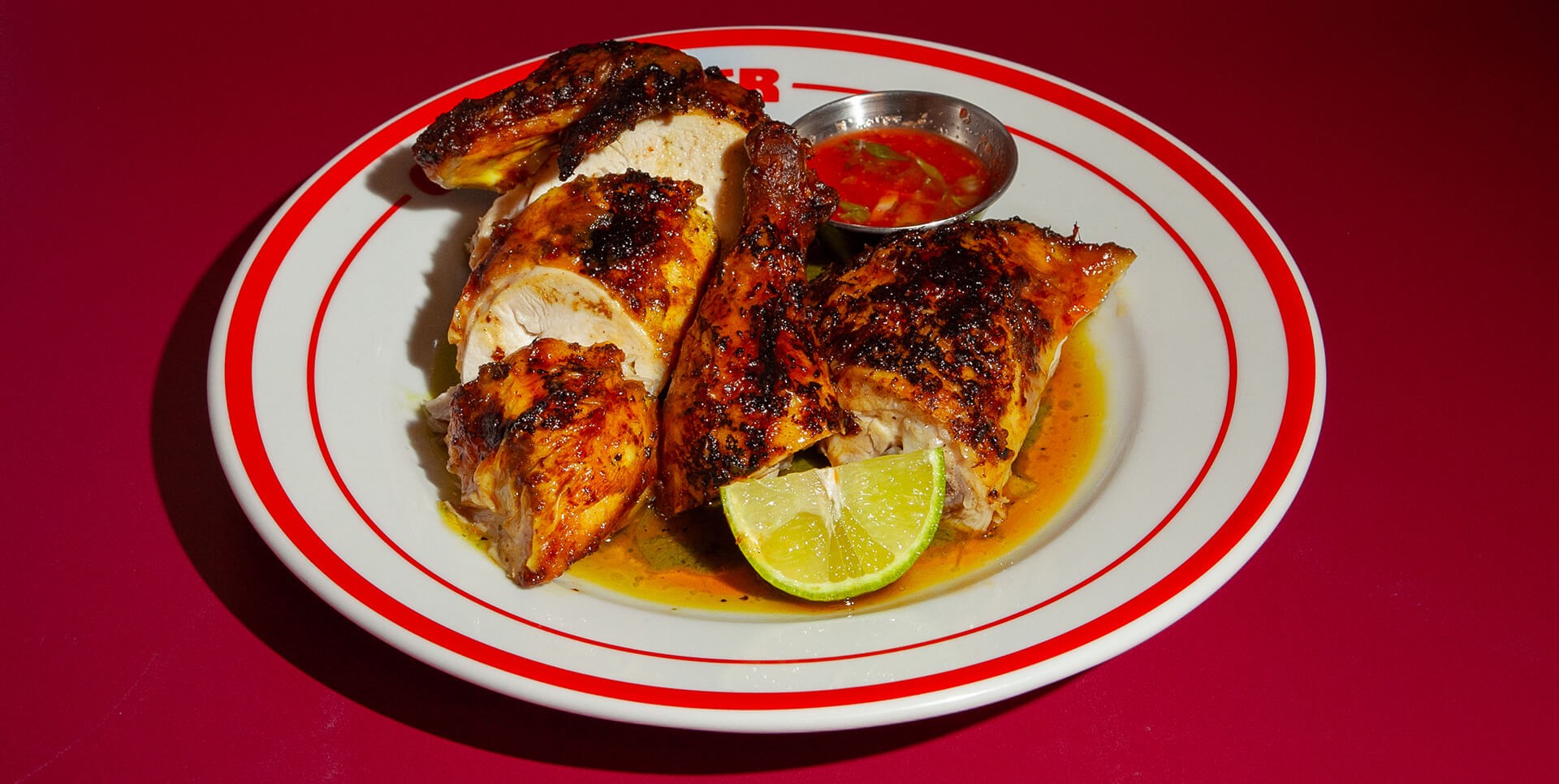 A close-up of a plate featuring a juicy and tender selection of chicken with lime and dipping sauce.